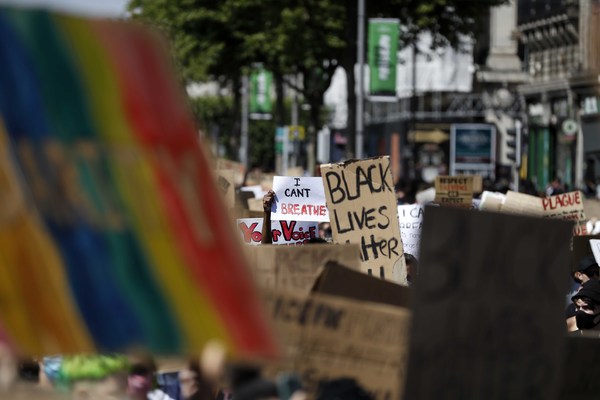 Image of Black Lives Matter protest featuring signs with the rainbow flag. 