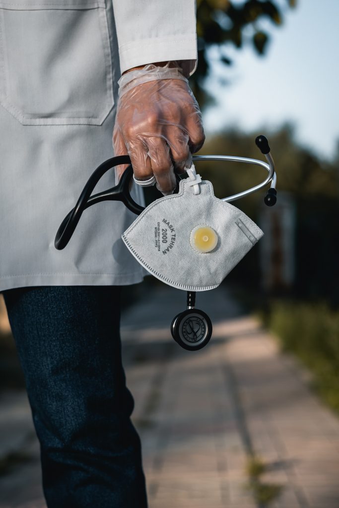 An image of a doctor holding a stethoscope and a mask. 