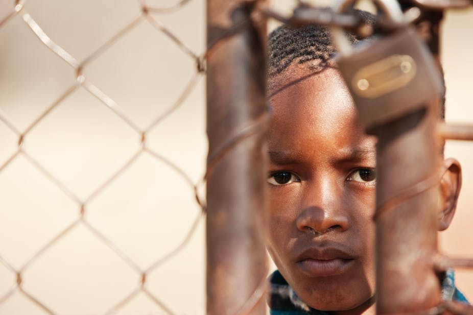 Image of a young boy looking through a closed gate