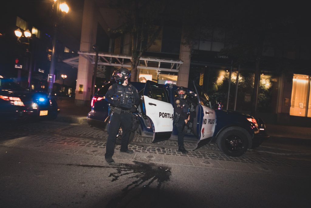 A photo of two armed police officers standing disembarking from their squad car