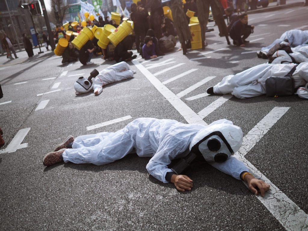 Photo of activists in nuclear protection suits laying on the ground