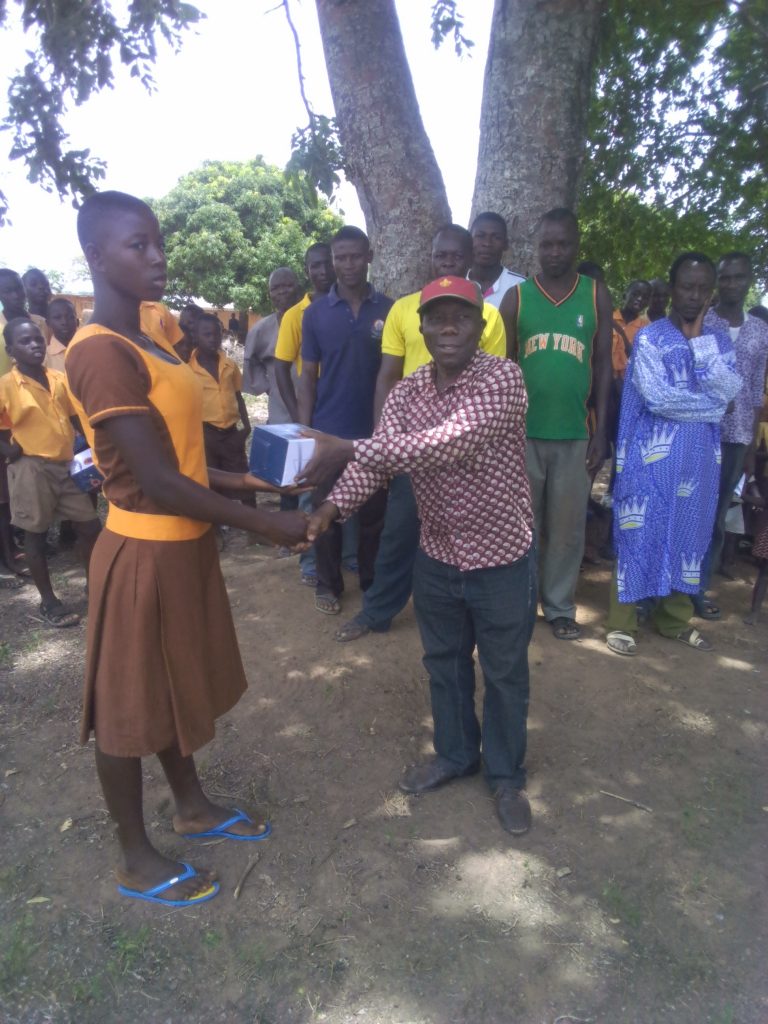 Mr Ofori, a volunteer presenting a solar reading light to a pupil at B-Zongo.