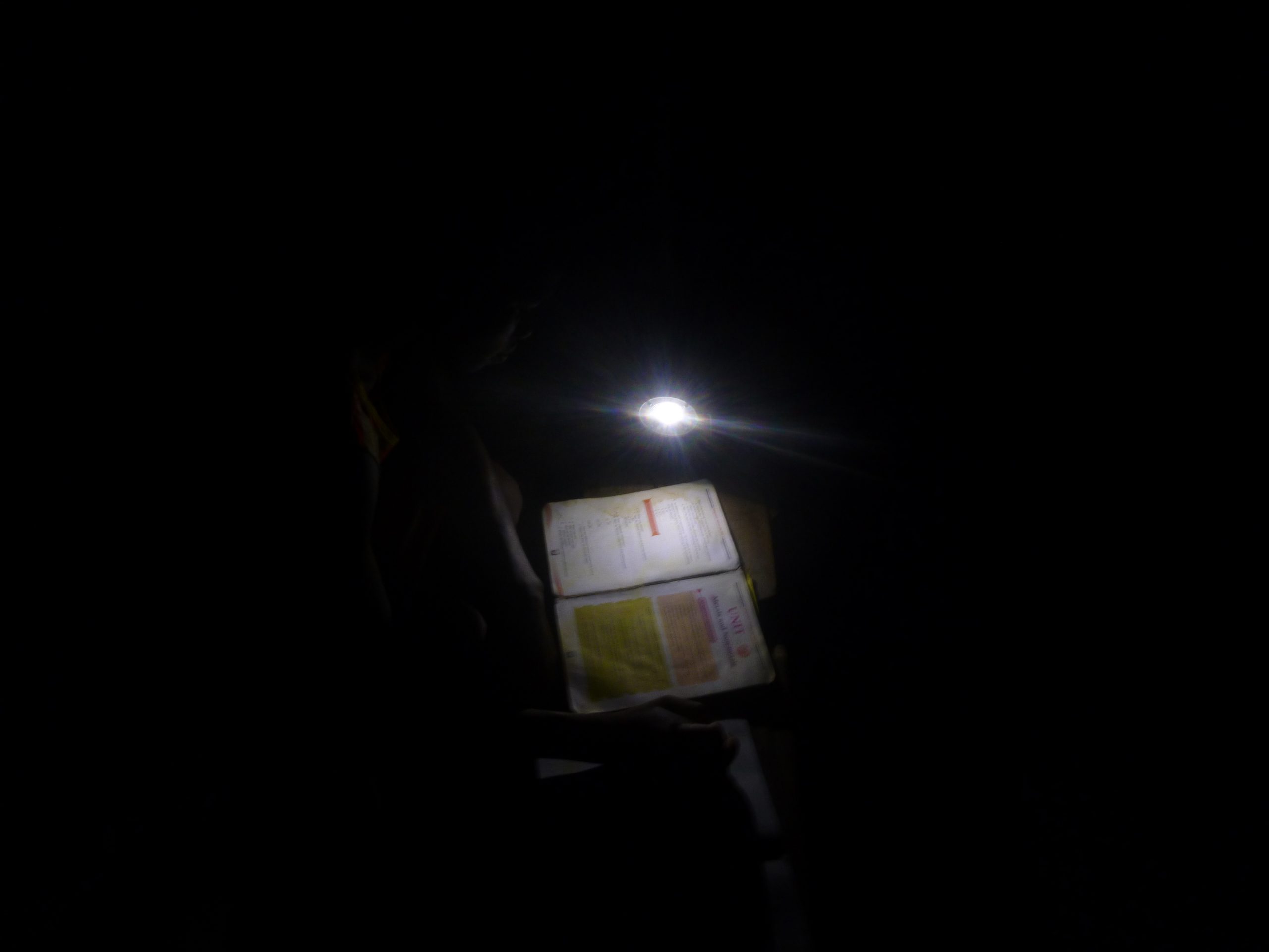 As a volunteer, I took this picture of this student learning with a solar light at night.