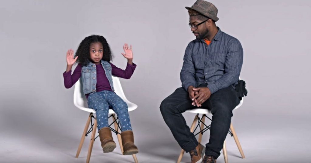 Image of an 8 year old black child holding up her hands, demonstrating how she is supposed to act in police presence.