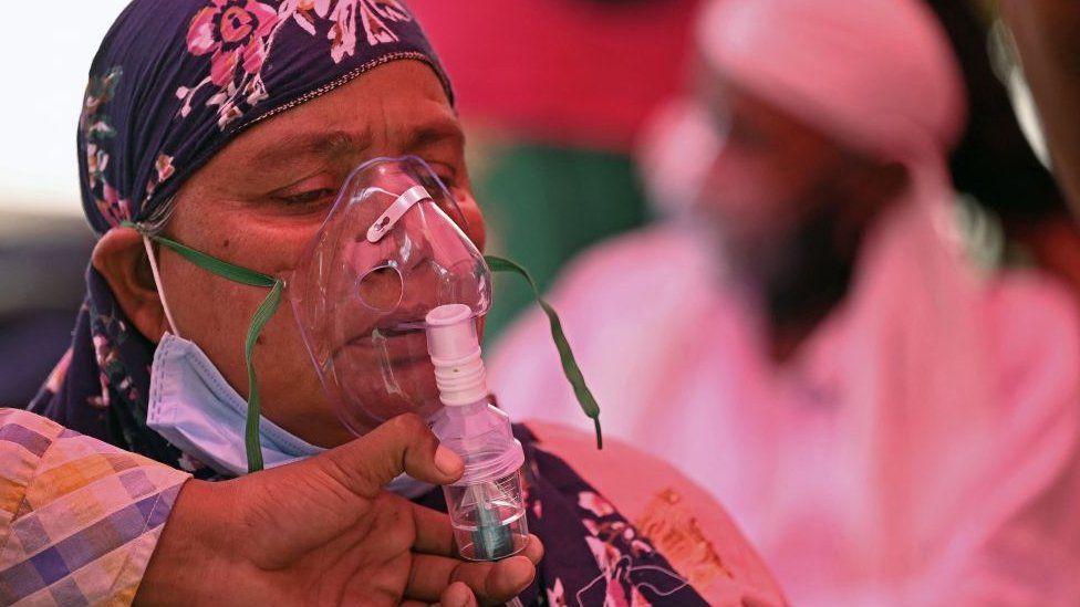 An image of an oxygen mask being placed on a woman.  