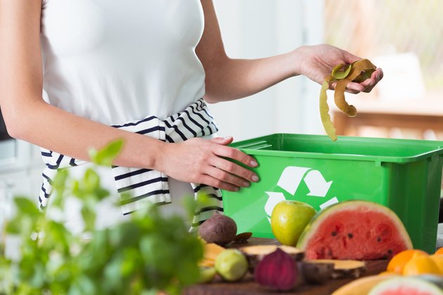 Image of a woman throwing decomposable food waste into a recycle bin.