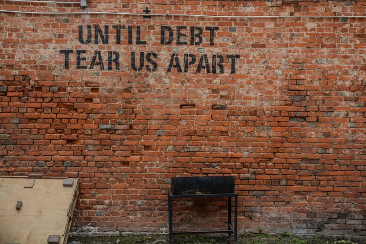 Image of a graffiti saying "until debt tear us apart"