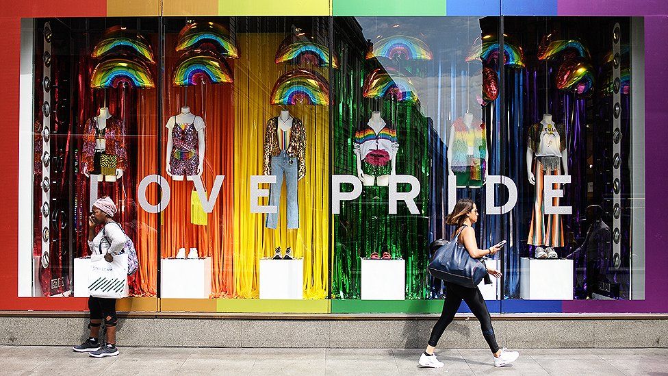 Store front displaying a Pride themed sale of products with rainbows.