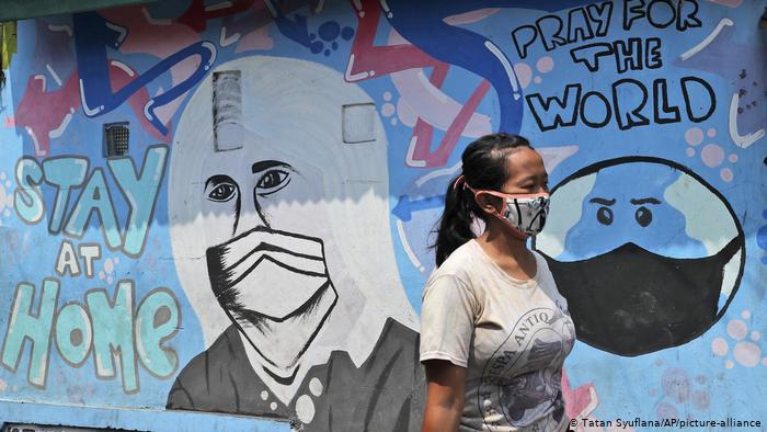 Woman walking past a Covid-19 mural. 