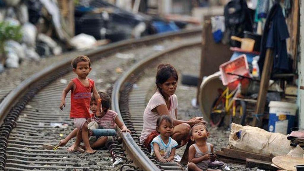 A woman and children sitting on a railway track near slums in Indonesia. 