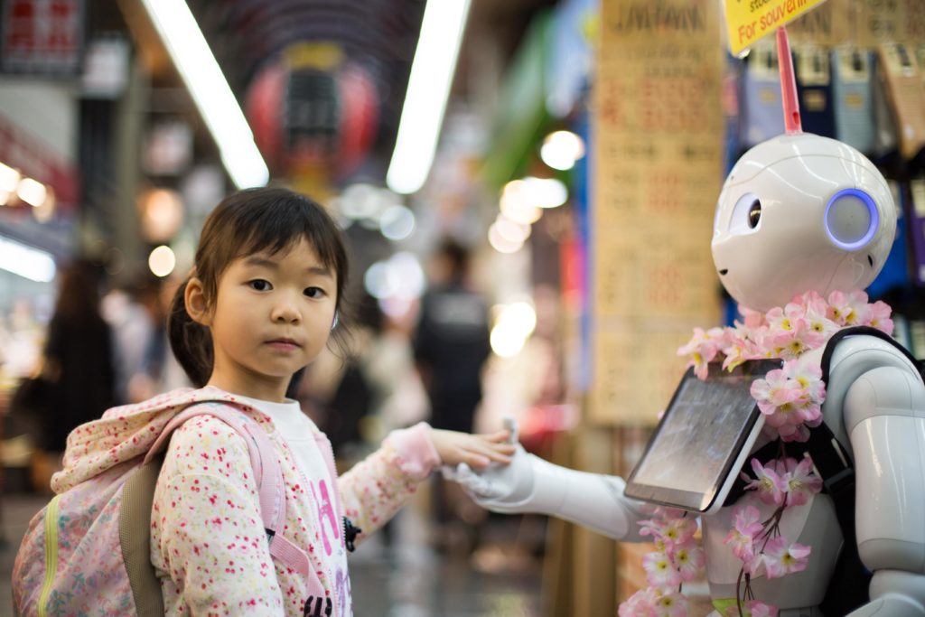 Image of a girl putting her hand on a robot in the streets of Asia