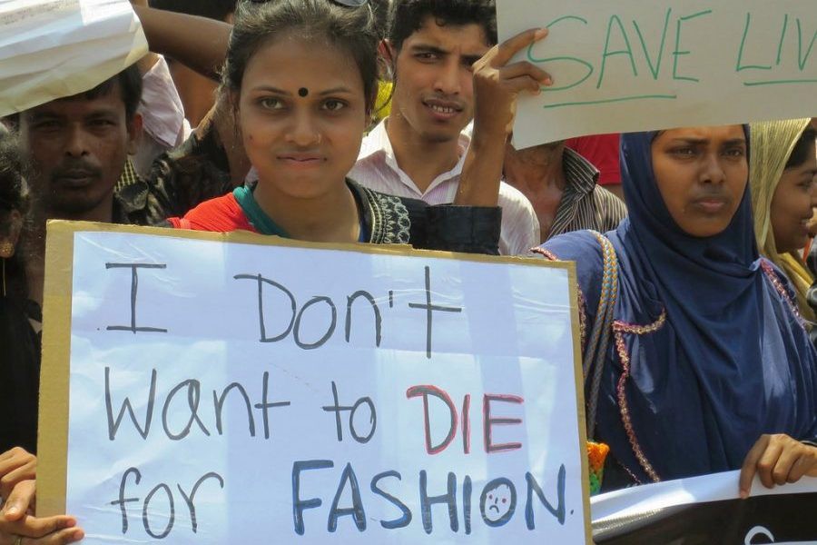 Women in Asia protesting against fast fashion holding a postcard written on it "I don't want to die for fashion"