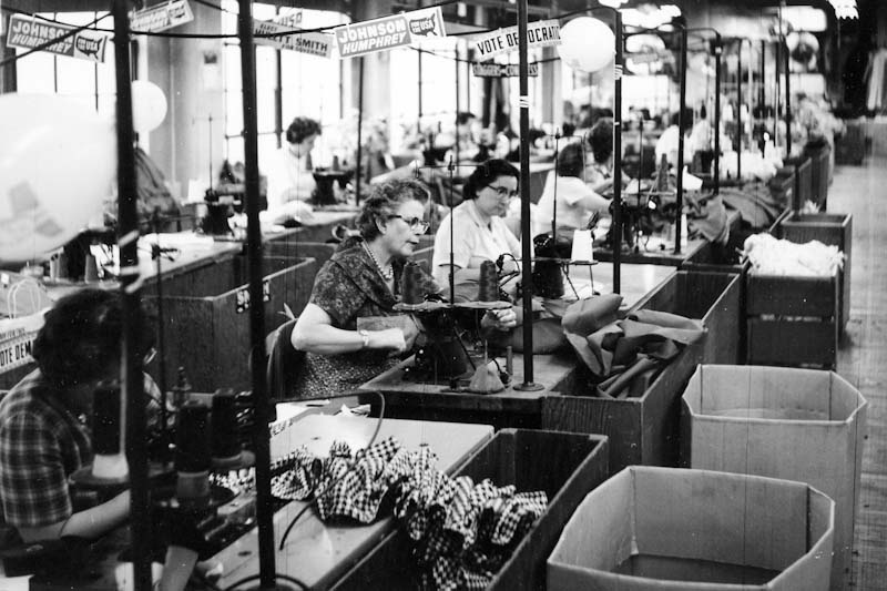 Picture in black and white of women using sewing machine.
