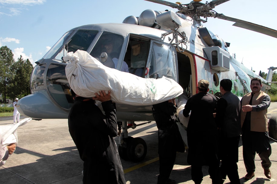 State officials unloading tents and essential supplies for flood victims off of a government helicopter. 