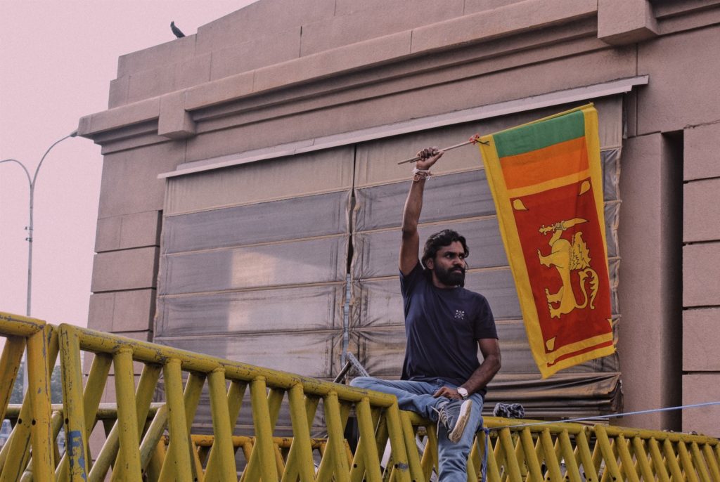 Photo of man holding the Sri Lankan flag above his head. Image credit: Kris Thomas