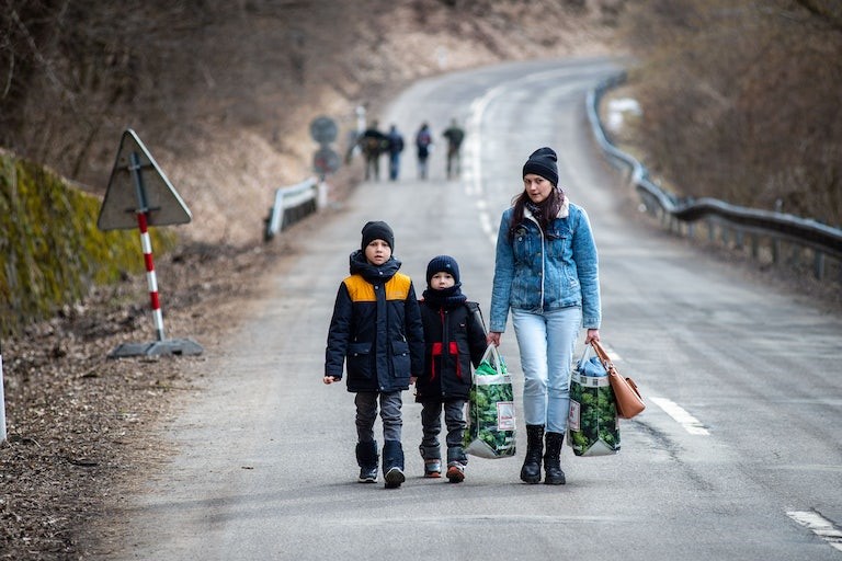 woman with 2 children on the road, fleeing to safety