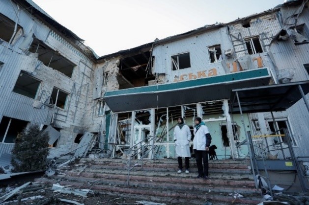 two medical personnel standing outside a destroyed medical facility